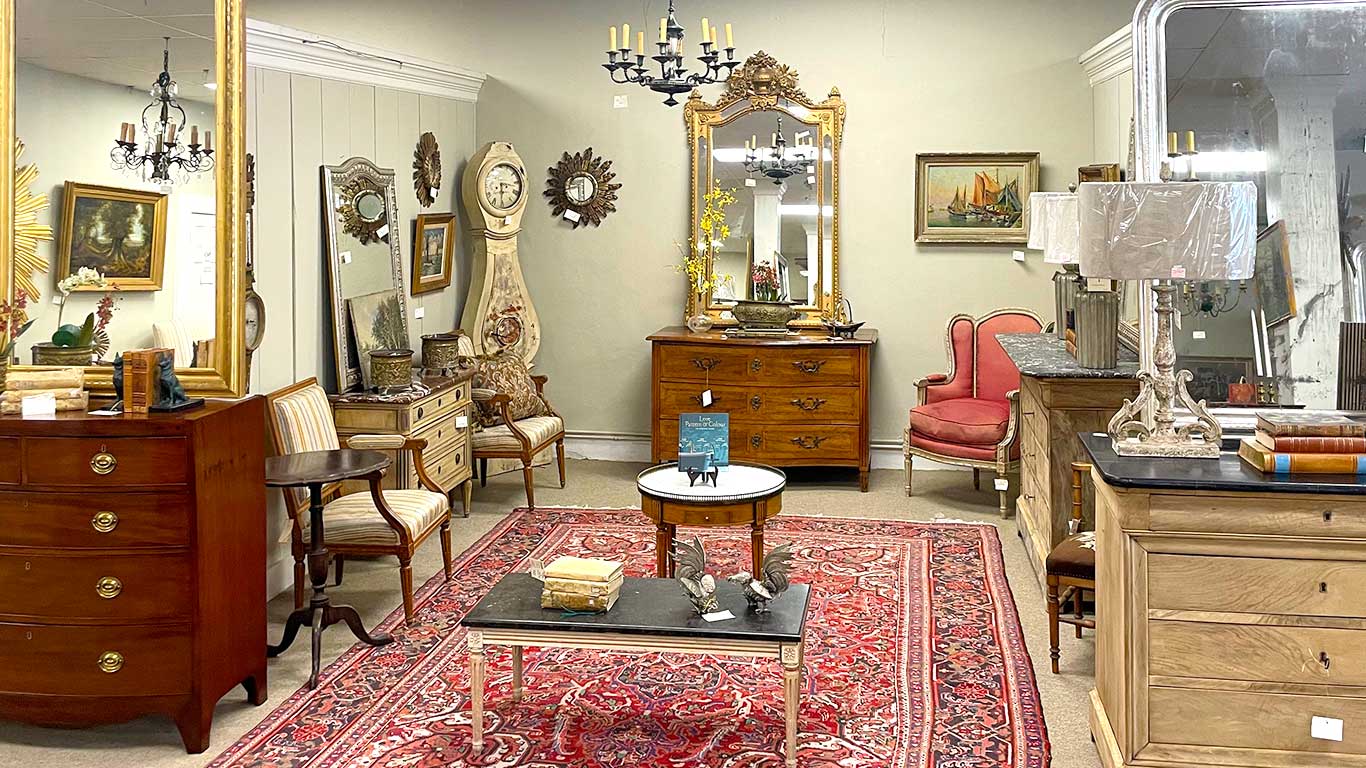 Inside Crown and Colony Antiques showroom with oriental rugs, credenza, chairs, mirrors and decorative accessories